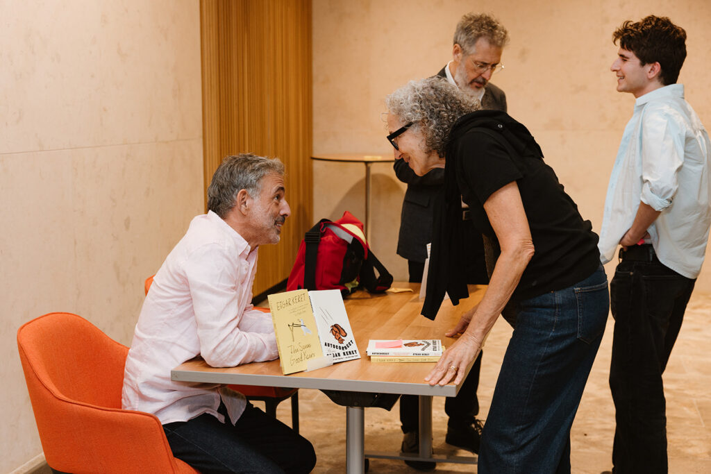 Edgar Keret signs books with Ira Glass signing in the background